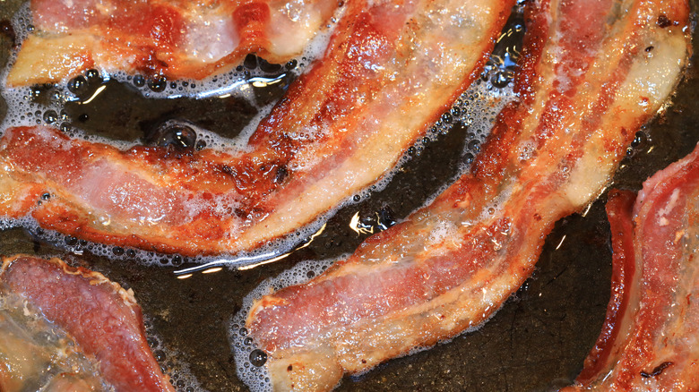 Closeup of bacon strips sizzling in oil