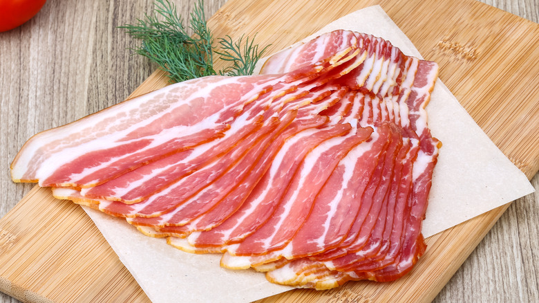 Sliced raw bacon on a wooden board