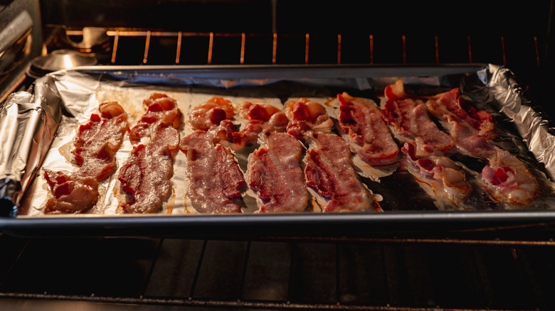 A baking tray of bacon slices in the oven