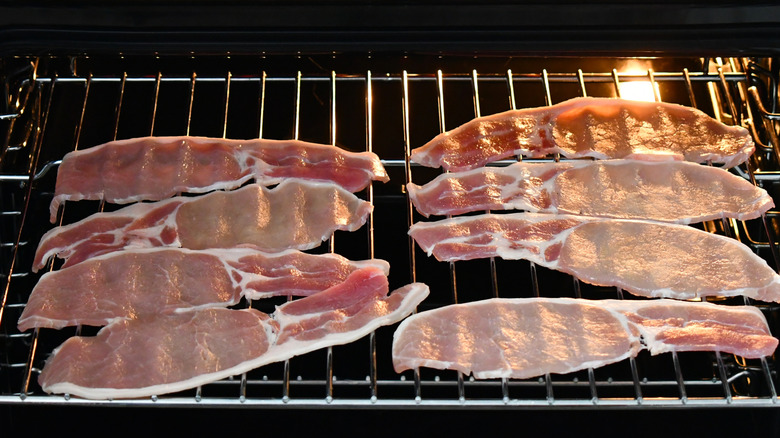 Bacon strips cooking on the cooling rack of an oven