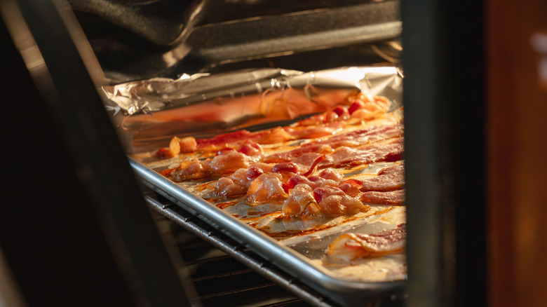 Open oven with baking sheet of bacon strips