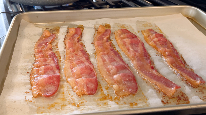 Bacon slices on parchment paper on baking sheet