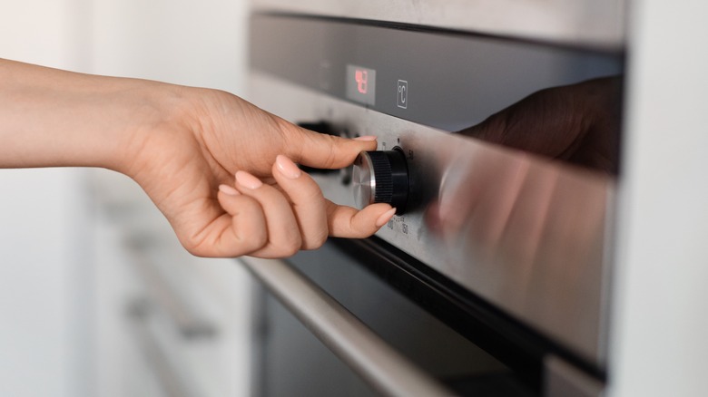 Person setting temperature on oven