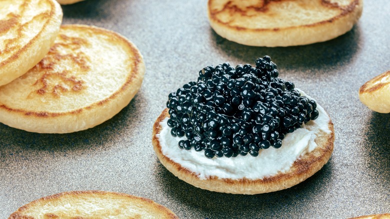 Blini topped with cream and caviar