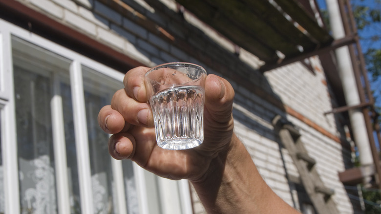 man holding a glass of vodka in a shot glass