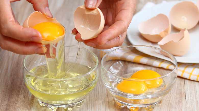 hands separating eggs into bowls