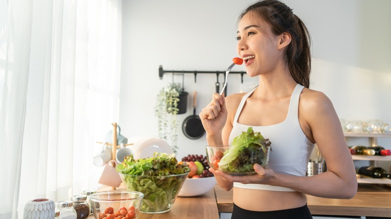 Person eating salad in kitchen