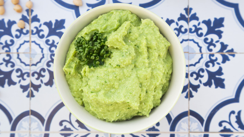 Avocado hummus in a bowl on a blue patterned countertop