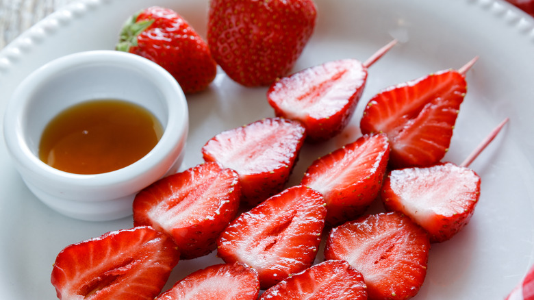 strawberry skewers with honey on plate