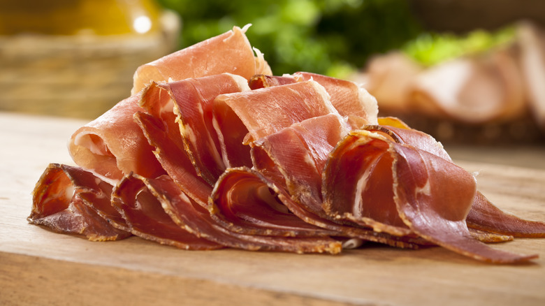 sliced prosciutto on wooden board