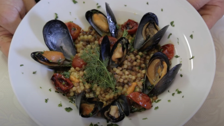 Hand holding bowl of fregola pasta 