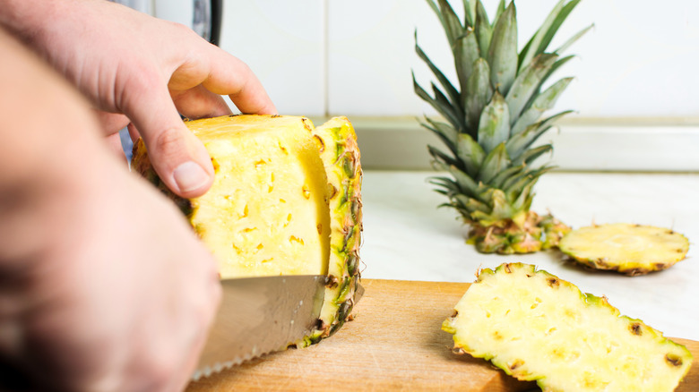 Person peeling a pineapple