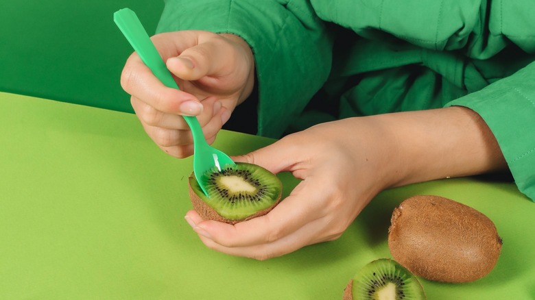 Person peeling a kiwi