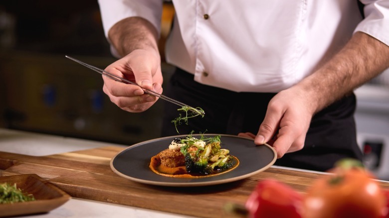 Chef using tweezers to garnish plate