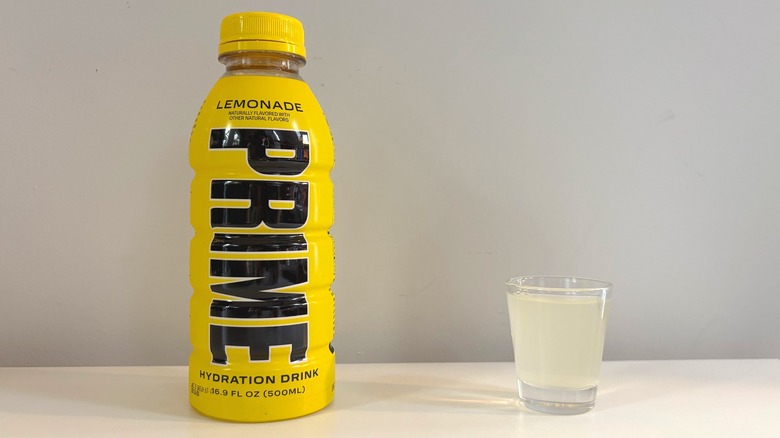 Prime Lemonade bottle next to shot glass with drink on white table