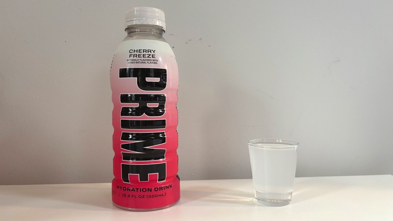 Prime Cherry Freeze bottle next to shot glass with drink on white table