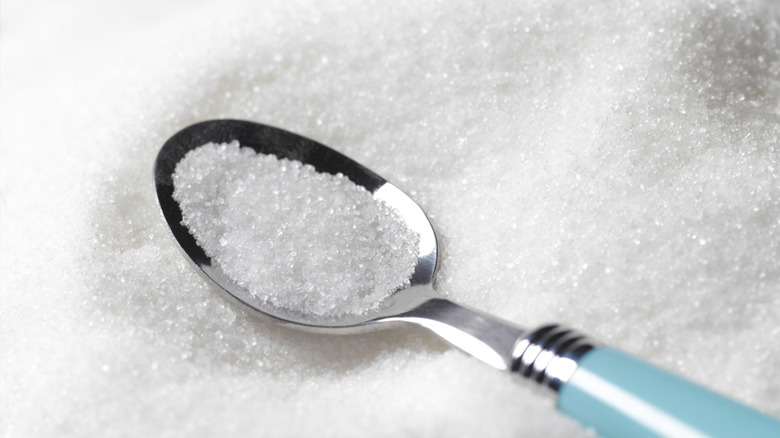 Teaspoon filled with sugar placed on loose sugar