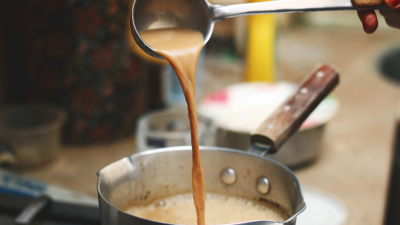 Person using ladle with pot on stovetop