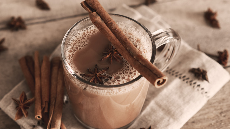 A cup of Indian masala chai with spices on a wooden background