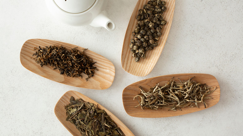 Top view of various loose leaf teas on bamboo plates