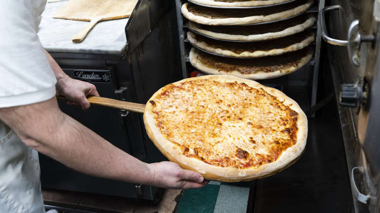 Chef putting pizza in oven