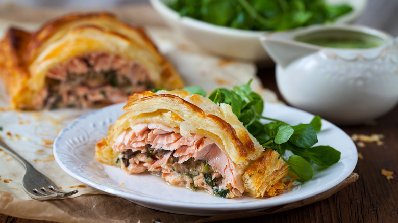 Slice of salmon en croute on plate with salad