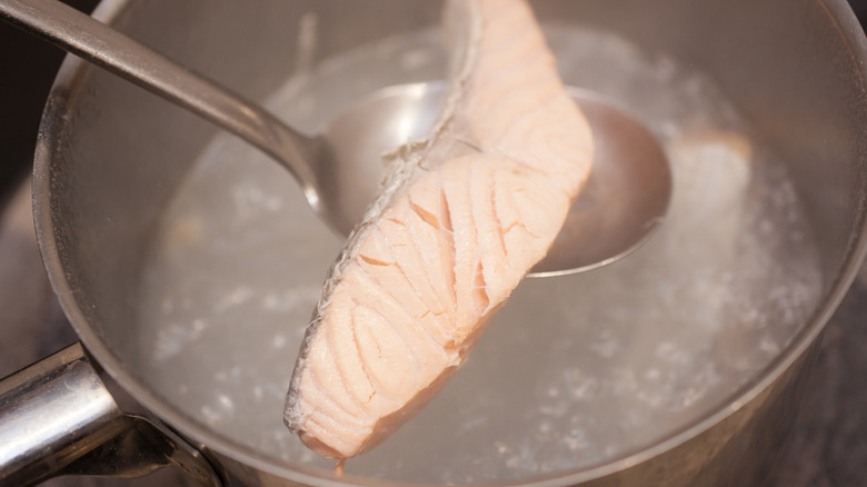 Salmon filet being lifted from pot of boiling water