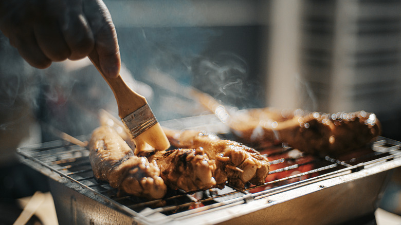 Person brushing chicken with marinade