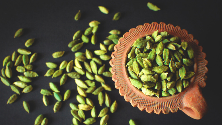 Green Cardamom in a clay container. Studio shot.