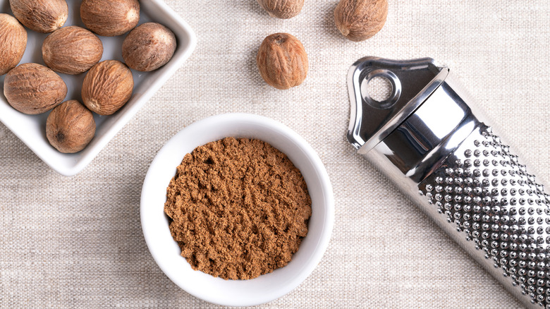 Nutmeg powder, ground nutmeg in a small white bowl on linen fabric.