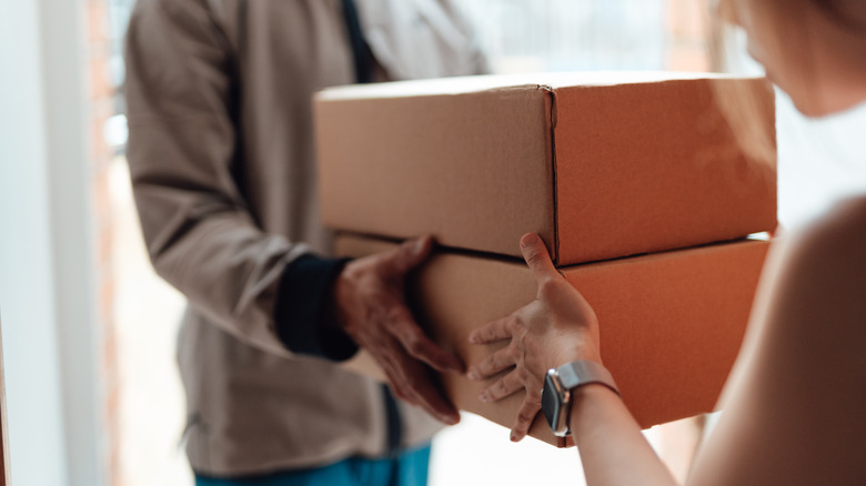 Two people are exchanging two shipping boxes.