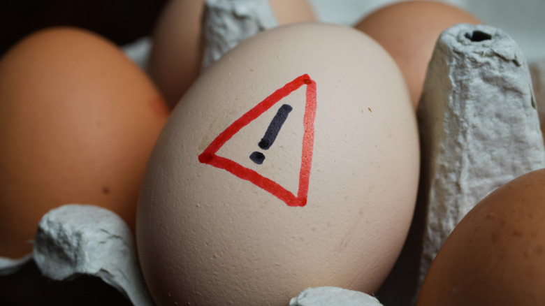 An exclamation point with a red triangle around it is drawn on an egg.