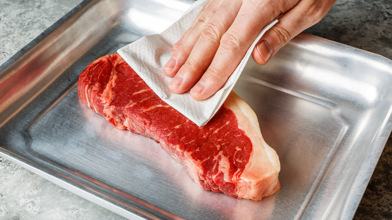 patting steak with paper towel