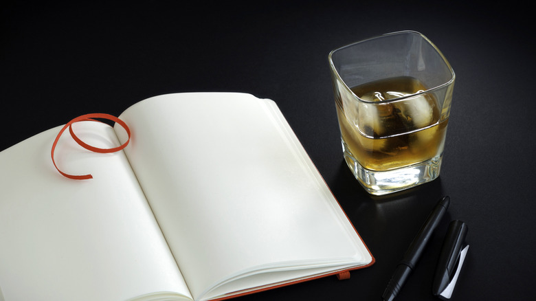 glass of bourbon with notebook