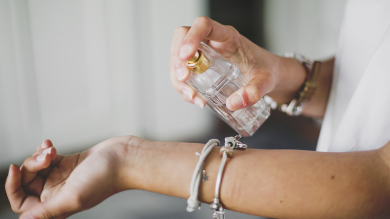 Person spraying perfume onto their wrist