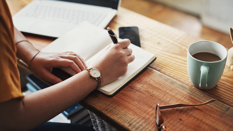 Person taking notes in notebook with pen