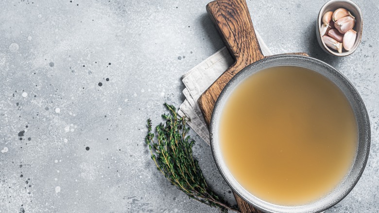 Broth in pan resting on wooden board 