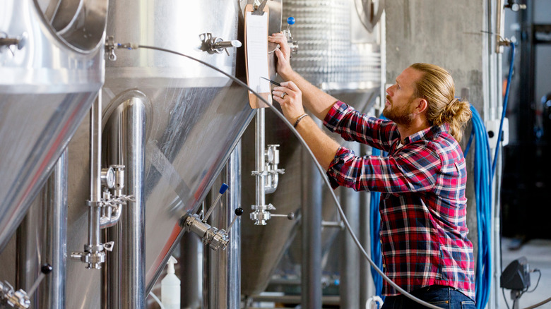 man checking tanks at distillery