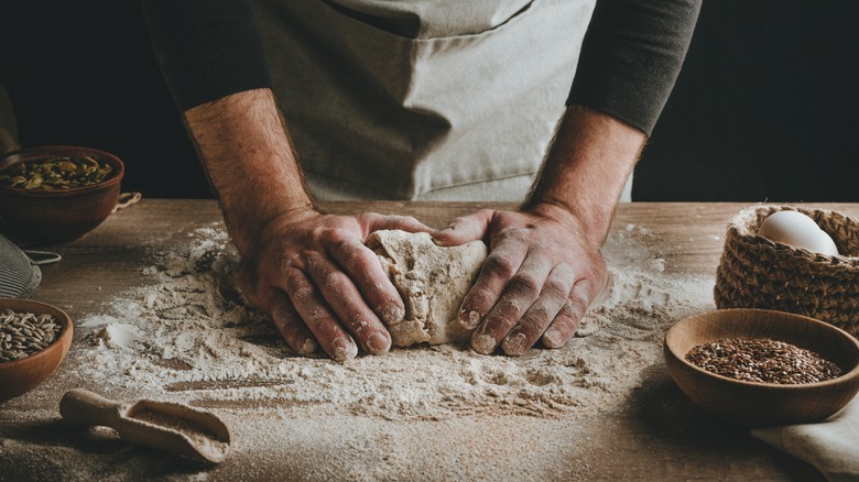 Hands kneading bread with ingredients