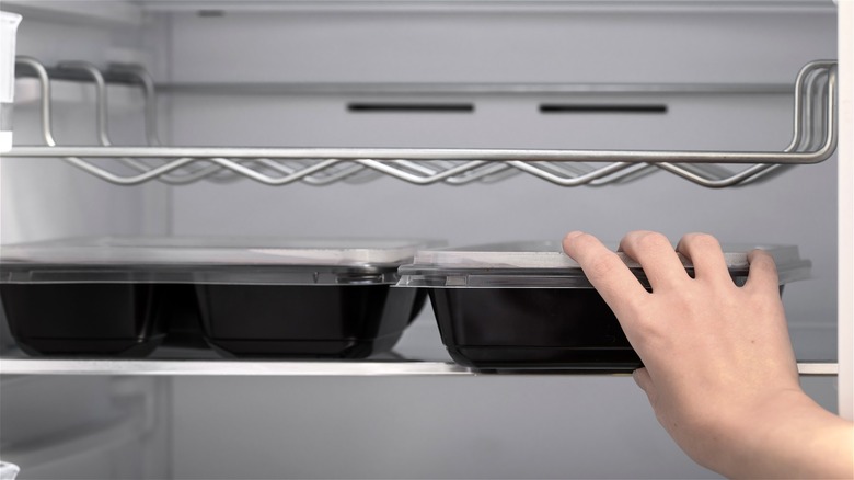 Hand putting container into refrigerator