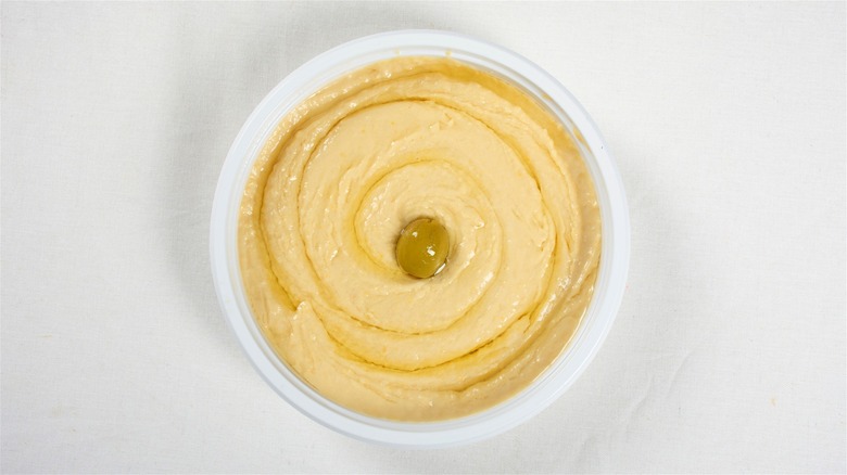 Oil-topped hummus in plastic tub