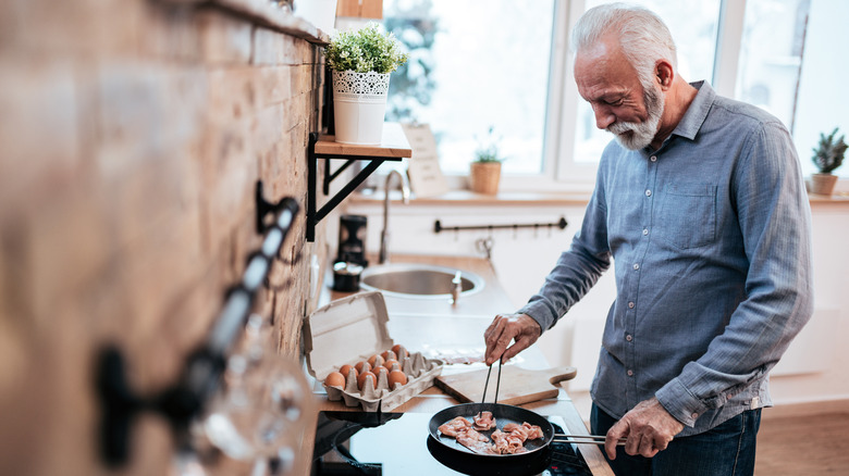 A man cooks bacon