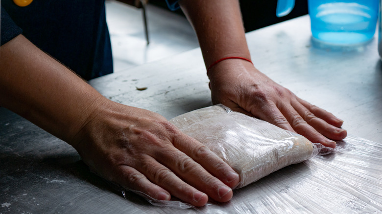 hands wrapping dough in plastic