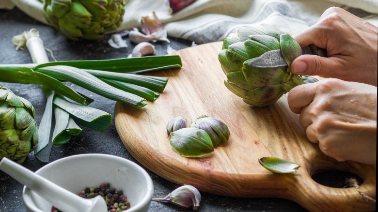 Hands prepping artichoke