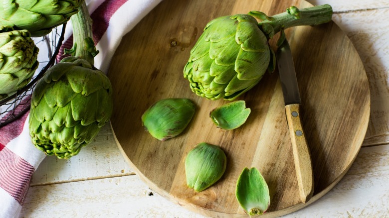 Raw artichoke on cutting board