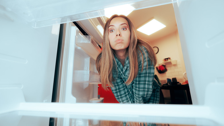 Woman looking into a fridge, concerned