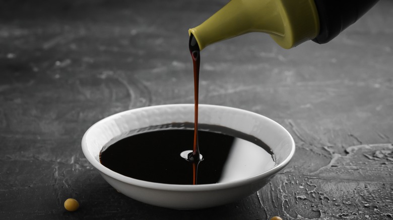 Bottle pouring soy sauce into dish