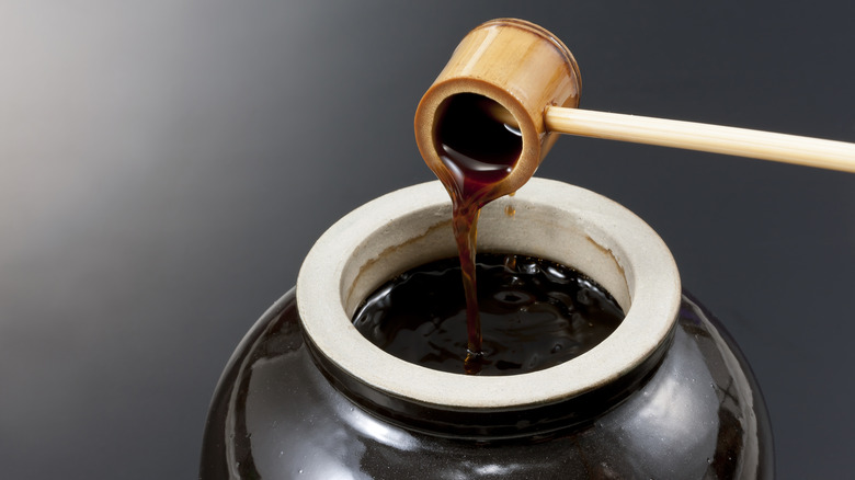 Wooden scoop pouring black vinegar