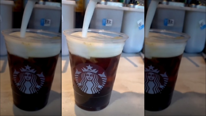 pouring cold foam on coffee