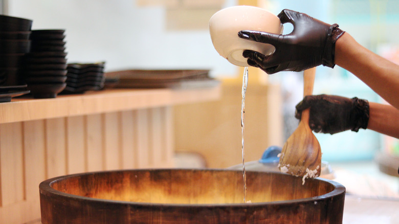 Hand pouring liquid into cooker